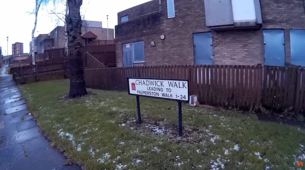 An image showing a street sign and boarded up buildings.